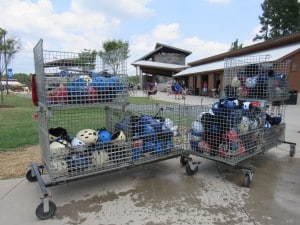 Many helmets inside a metal cart outside of a building.